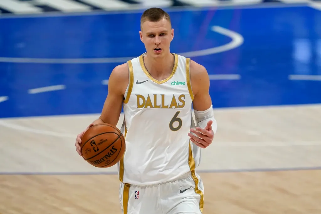 Kristaps Porzingis 穿著達拉斯小牛隊（Dallas Mavericks）球衣，持球準備進攻，背景為籃球場。