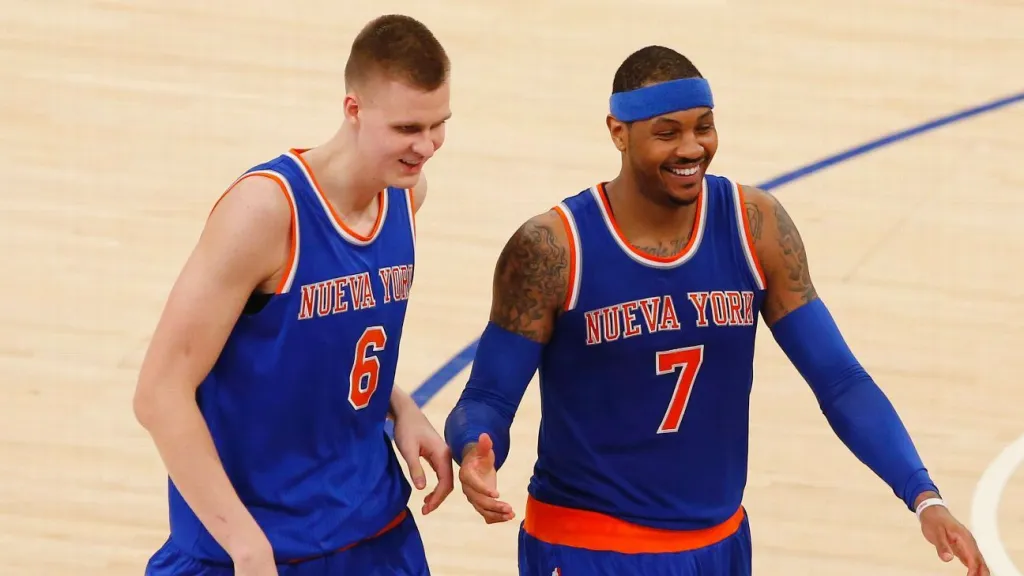 Kristaps Porzingis 和 Carmelo Anthony 穿著紐約尼克隊球衣，在場上微笑並互動，展現出彼此的友誼和合作。